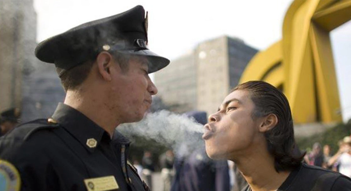 Man blowing cannabis smoke in a police officers face
